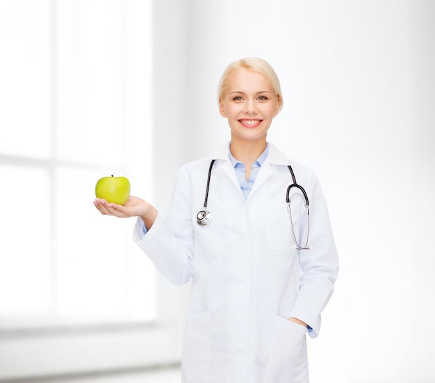 healthcare and medicine concept - smiling female doctor with stethoscope and green apple