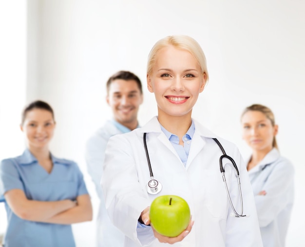 healthcare and medicine concept - smiling female doctor with stethoscope and green apple