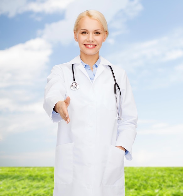 концепция здравоохранения и медицины - улыбающаяся женщина-врач со стетоскопом, готовая пожать друг другу руки