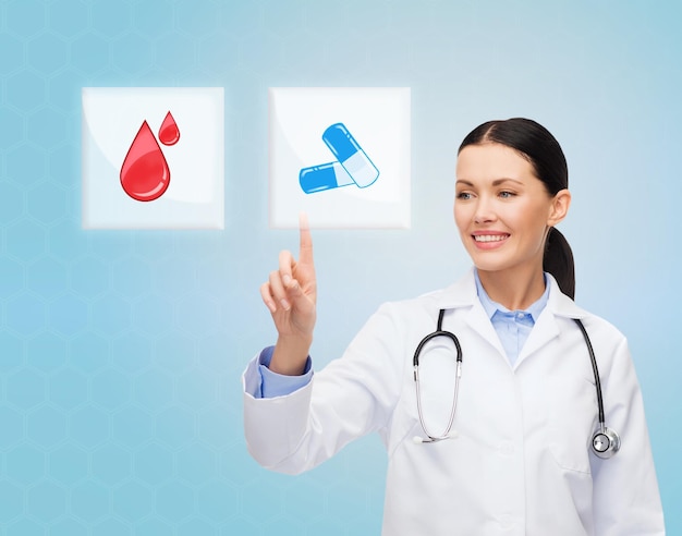 의료, 의학, 사람 및 기술 개념 - 파란색 배경 위에 아이콘을 가리키거나 알약과 혈액 이미지가 있는 버튼을 누르는 웃는 젊은 의사 또는 간호사