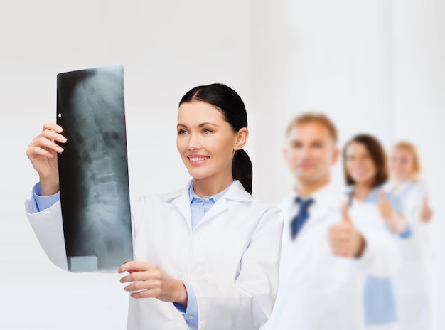 концепция здравоохранения, медицины и радиологии - улыбающаяся женщина-врач, смотрящая на рентген