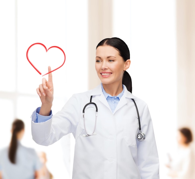 healthcare, medicine and technology concept - smiling female doctor pointing to heart