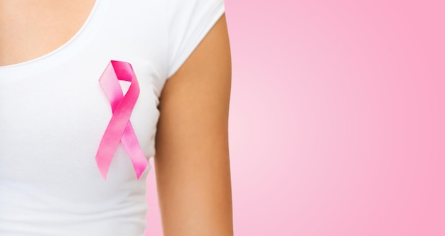концепция здравоохранения, людей, благотворительности и медицины - крупный план женщины в футболке с лентой для информирования о раке молочной железы на розовом фоне