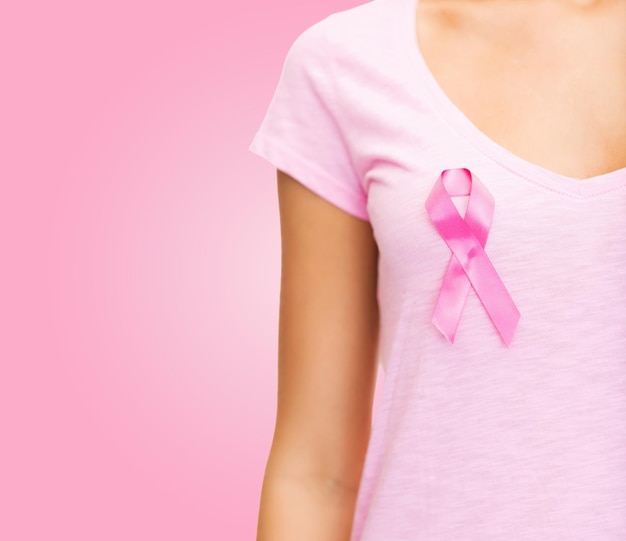 healthcare, people, charity and medicine concept - close up of woman in t-shirt with breast cancer awareness ribbon over pink background