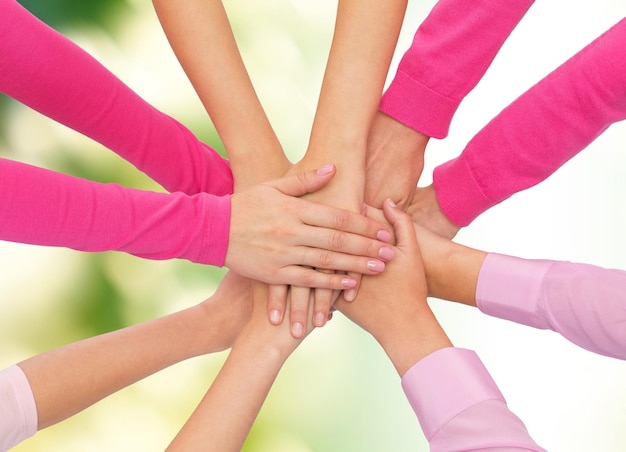 healthcare, people, gesture and medicine concept - close up of women hands on top of each other over green background