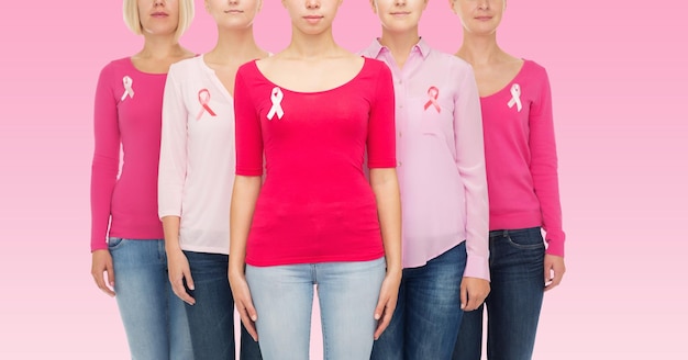 Photo healthcare, people and medicine concept - close up of women in blank shirts with breast cancer awareness ribbons over pink background