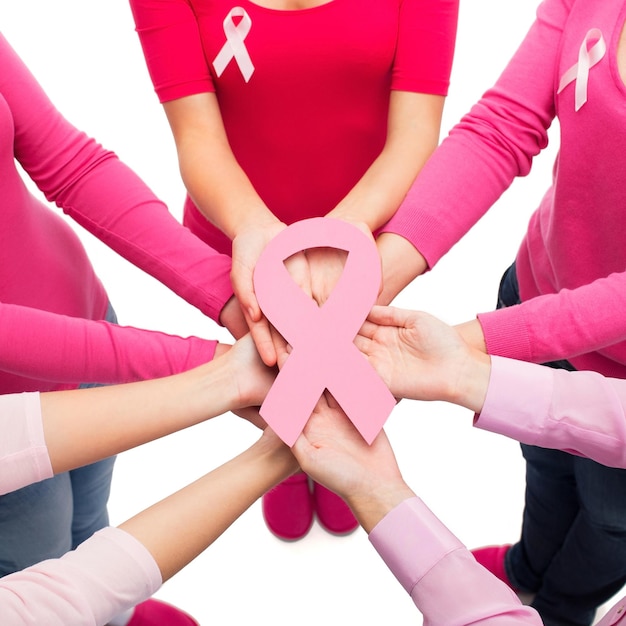 Photo healthcare, people and medicine concept - close up of women in blank shirts with pink breast cancer awareness ribbons over white background