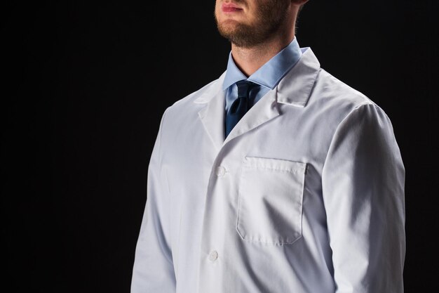 healthcare, people, profession and medicine concept - close up of male doctor in white coat over black background