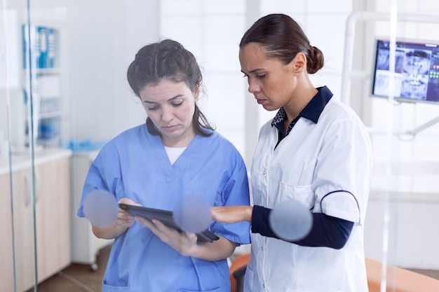 Healthcare personal in stomatology office talking about teet healing procedure. orthodontic specialist and assistant dental clinic discussing about teeth treatment.