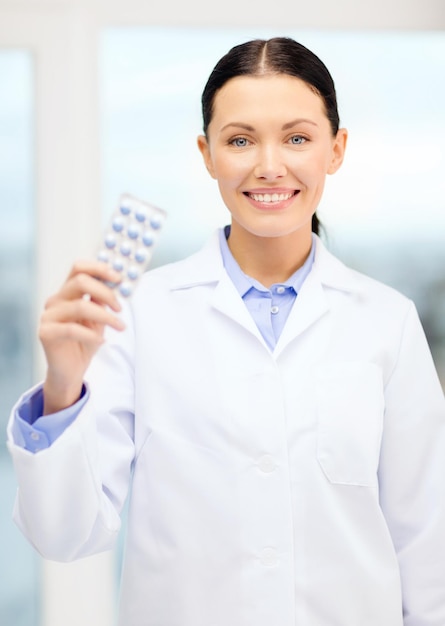 healthcare, pharmacy and medicine concept - smiling young doctor with pills in cabinet