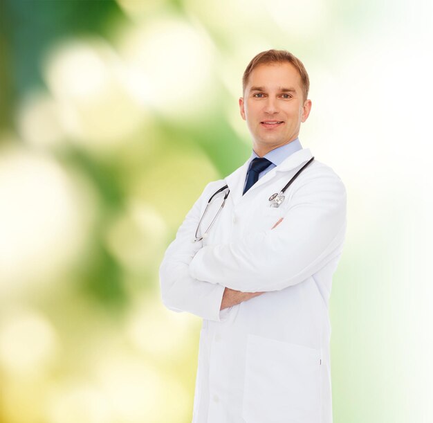 의료, 직업, 환경 및 의학 개념 - 자연 배경 위에 흰색 코트를 입은 청진기를 들고 웃고 있는 남성 의사
