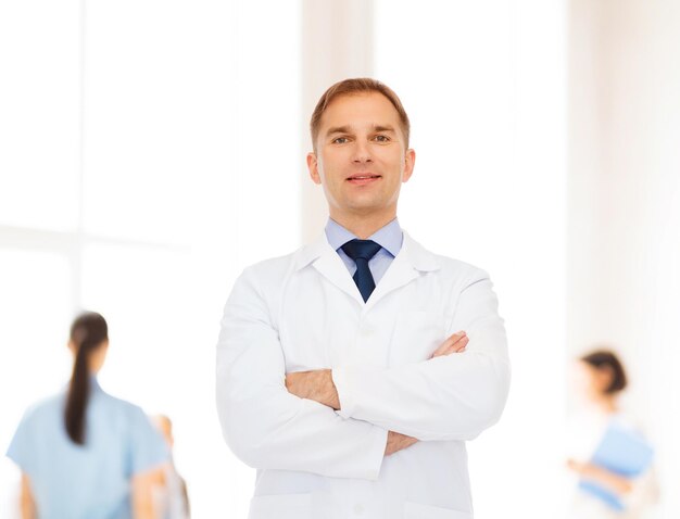 healthcare, profession, teamwork and medicine concept - smiling male doctor in white coat over group of medics