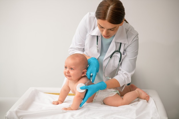 Healthcare professional concentrated on vaccinating a newborn patient