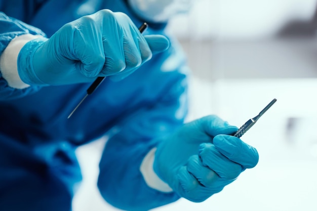 Healthcare surgeon and hands with a scalpel for procedure in an operating room at hospital Closeup of doctor or nurse with medical equipment for surgery in emergency room at medicare clinic center