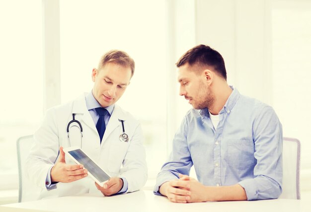 healthcare, technology and medicine concept - serious doctor with tablet pc computer and patient in hospital