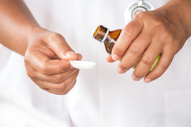 Healthcare, treatment and medicine concept - bottle of medication or antipyretic syrup and spoon