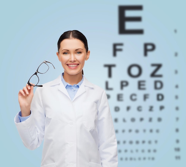 healthcare, vision and medicine concept - smiling female doctor with glasses and eye chart