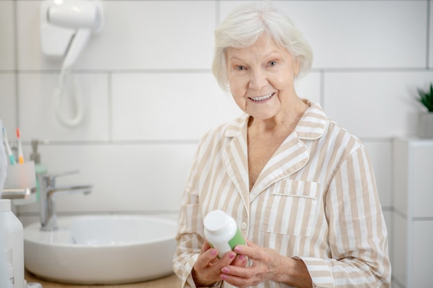 Healthcare. Woman in pajama holding a bottle with vitamins in her hands