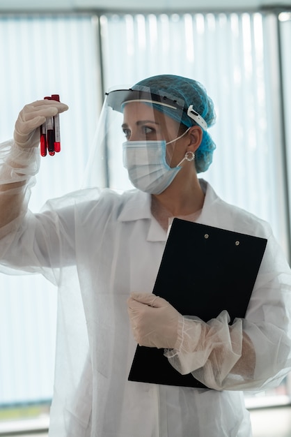 Healthcare worker hold clipboard with patient results and look on test tube. coronavirus pandemic