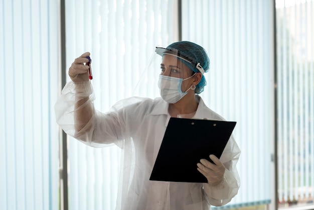 Healthcare worker hold clipboard with patient results and look on test tube