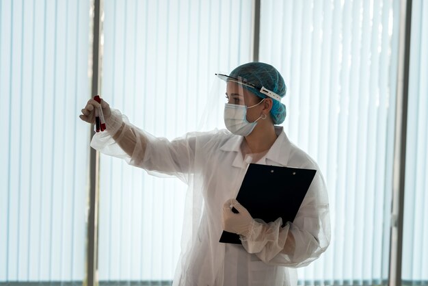 Healthcare worker hold clipboard with patient results and look on test tube