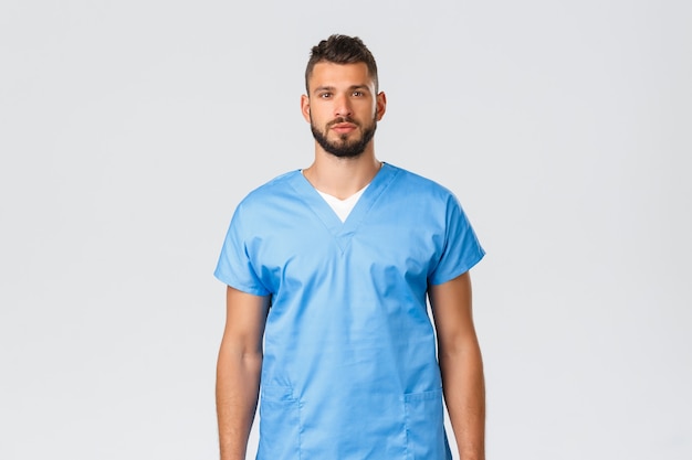 Healthcare workers, medicine, covid-19 and pandemic self-quarantine concept. Determined young doctor, physician in blue scrubs, battle agaisnt coronavirus, treating patients in hospital.