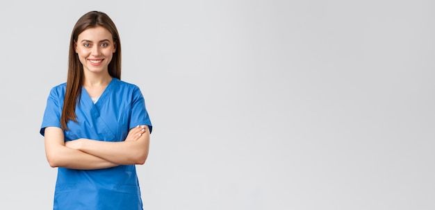 Foto gli operatori sanitari prevengono l'assicurazione contro i virus e il concetto di medicina fiduciosa infermiera medico in camice blu sorridente e petto a braccia incrociate pronta a salvare la vita del paziente sfondo grigio