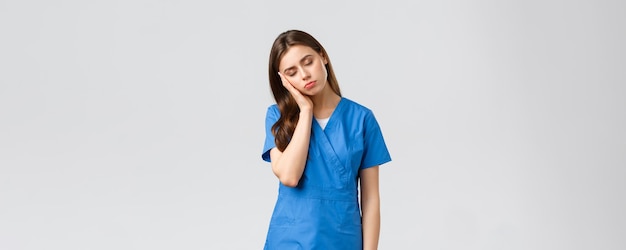 Healthcare workers prevent virus and medicine concept tired sleepy female doctor young nurse in blue