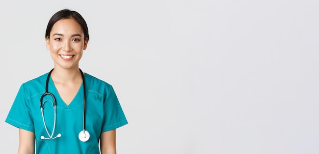 Healthcare workers, preventing virus, quarantine campaign concept. Close-up of smiling pleasant asian female nurse, physician in scrubs looking upbeat, listening to patient, white background