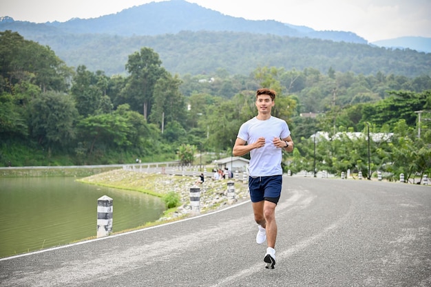 Healthy and active Asian man running or jogging at the beautiful lake Healthy lifestyle