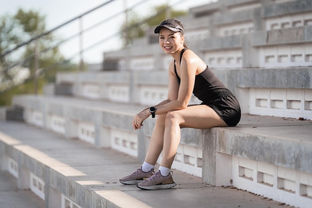 A healthy adult Asian woman running up on concrete stairs of the city stadium to strengthen body