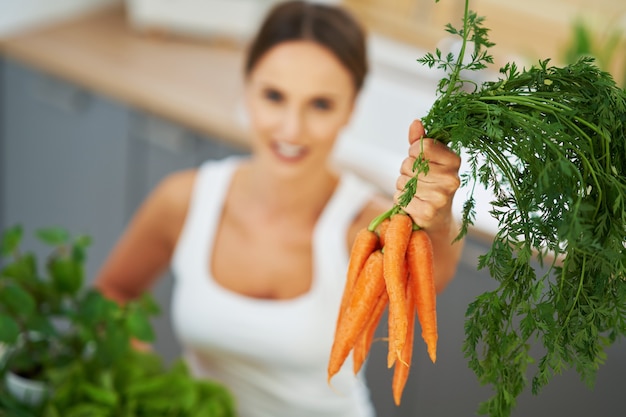 healthy adult woman with green food in the kitchen