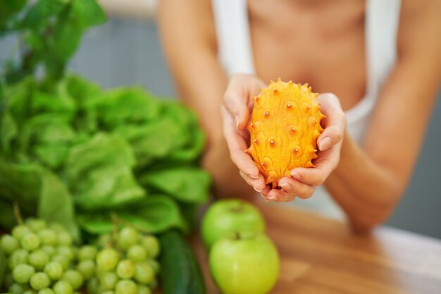 healthy adult woman with green food in the kitchen