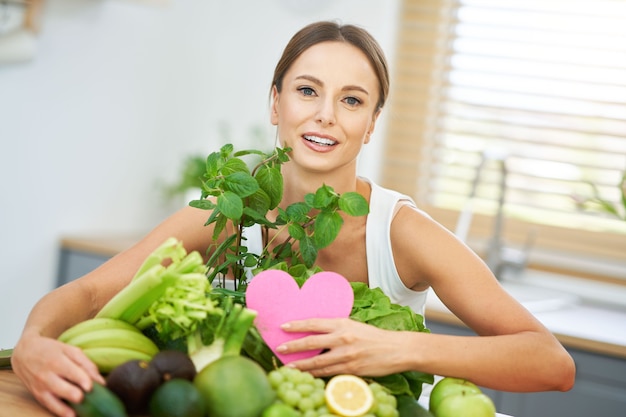 キッチンで緑の食べ物と健康な大人の女性