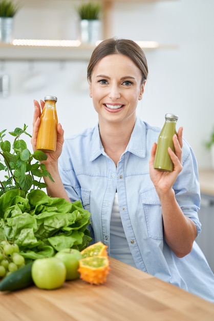 キッチンで緑の食べ物と健康な大人の女性