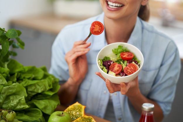 キッチンで緑の食べ物と健康な大人の女性