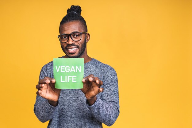 Здоровый афро-американский чернокожий мужчина держит яблоко, изолированное на желтом фоне. Концепция диеты здорового питания. Концепция веганского образа жизни.