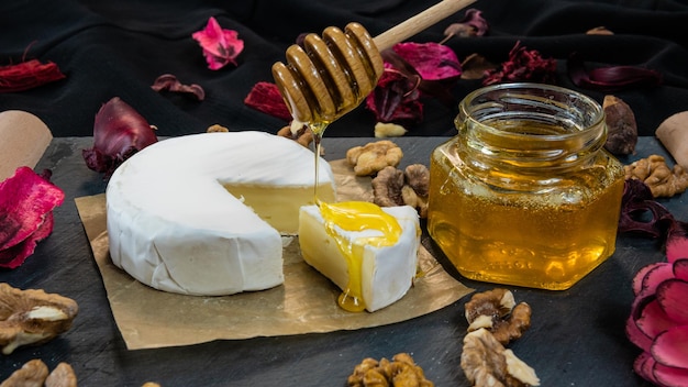 Фото Здоровая и вкусная еда сыр камамбер с орехами и медом сушеные цветы на темном фоне