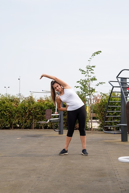 Healthy anf active lifestyle. Sports and fitness. Happy woman in white t shirt working out on the sports ground in sunny summer day, warming up