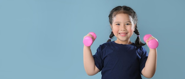 A healthy asian child girl playing dumbbell with strong look healthy Kid with strong muscle