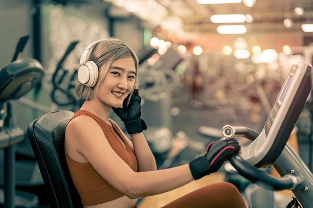 Foto donne asiatiche sane che ascoltano musica con le cuffie durante l'esercizio in palestra