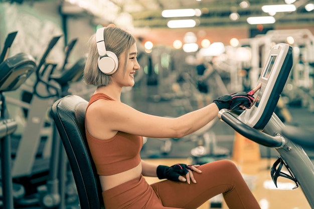 Donne asiatiche sane che ascoltano musica con le cuffie durante l'esercizio in palestra