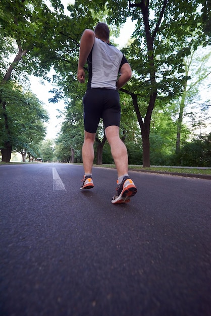 здоровый спортсмен бегает по утрам на пустой дороге в городе