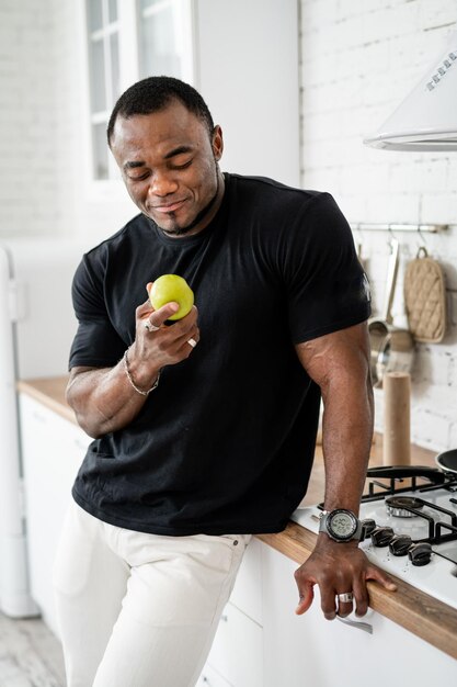 Healthy athletic man eating apple Strong lifestyle person indoor on kitchen