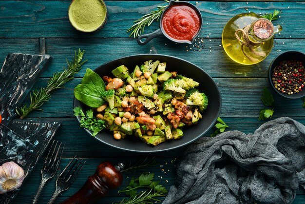 Healthy avocado salad chickpeas broccoli and chicken in a black stone plate Top view Free space for your text