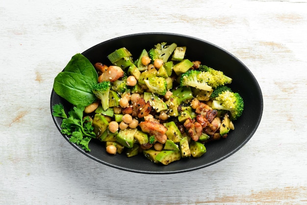 Healthy avocado salad chickpeas broccoli and chicken in a black\
stone plate top view free space for your text