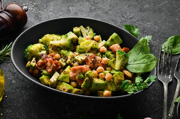 Healthy avocado salad chickpeas broccoli and chicken in a black stone plate Top view Free space for your text