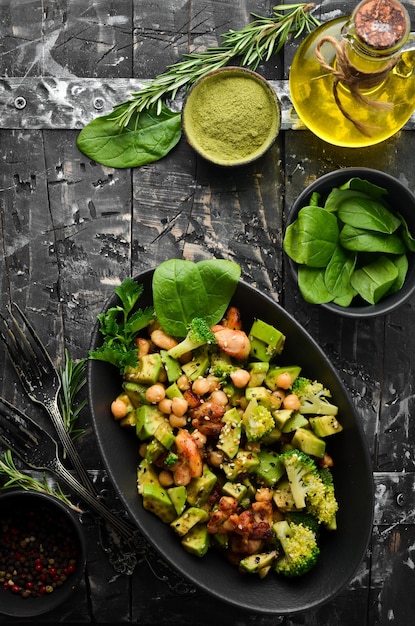 Healthy avocado salad chickpeas broccoli and chicken in a black\
stone plate top view free space for your text