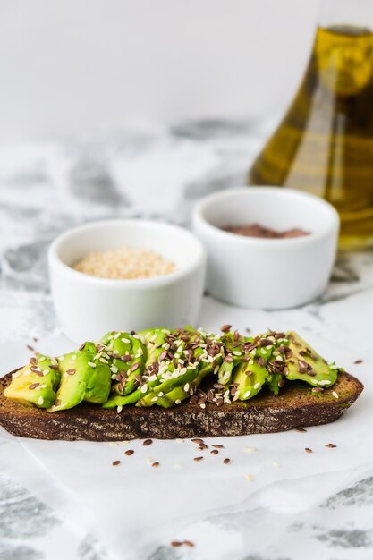 Healthy avocado toast on concrete background. wholegrain bread,\
sesame flax seeds olive oil. vegan keto diet. healthy eating.\
vegetarian trendy guacamole sandwich.