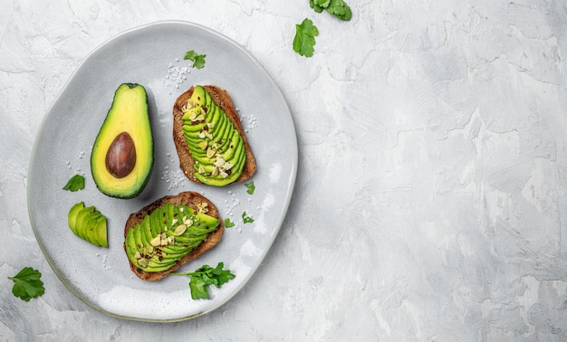 Healthy avocado toasts for breakfast or lunch with rye bread sliced avocado pumpkin seeds salt and pepper Vegetarian food Plantbased diet Clean eating Top view Copy space